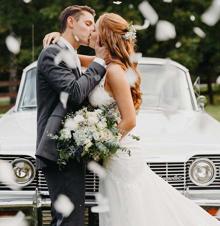 Couple kissing in front of classic car